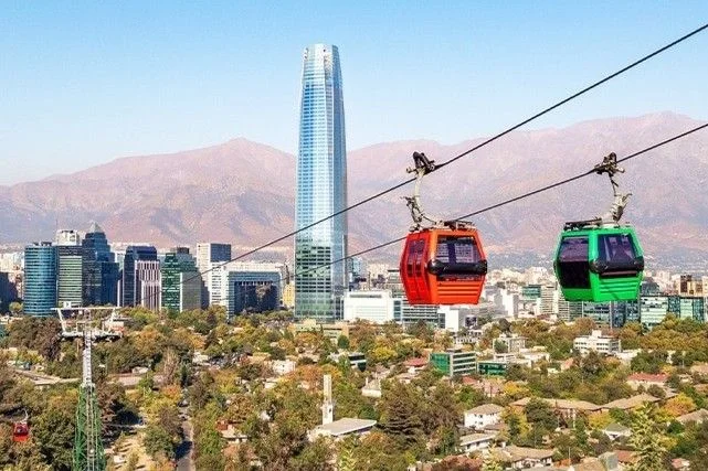 Panoramic view of Santiago de Chile with iconic landmarks and the Andes mountains.